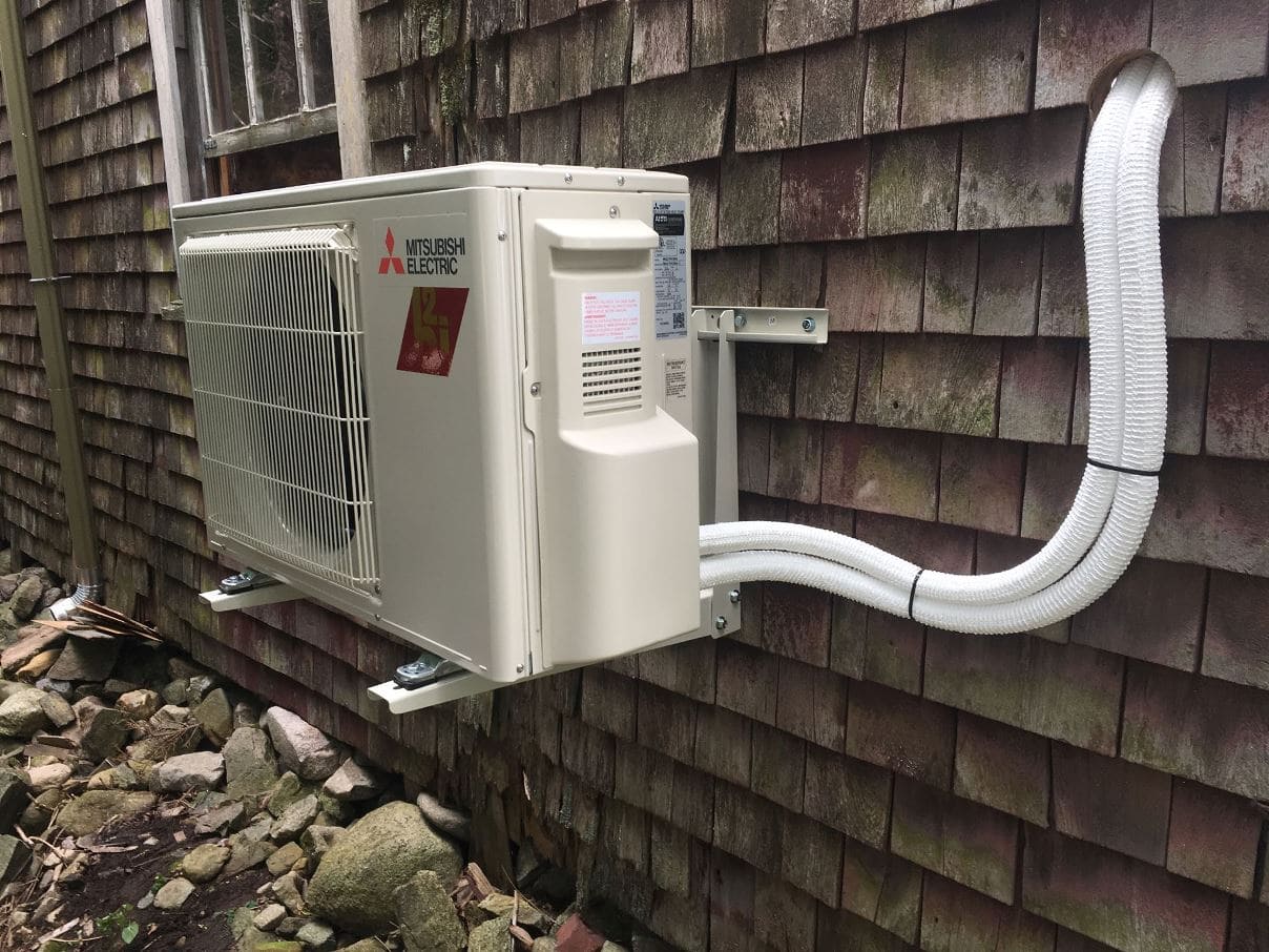 Energy-efficient Mitsubishi Electric outdoor mini-split HVAC unit installed on house wall, ideal for heating and cooling.