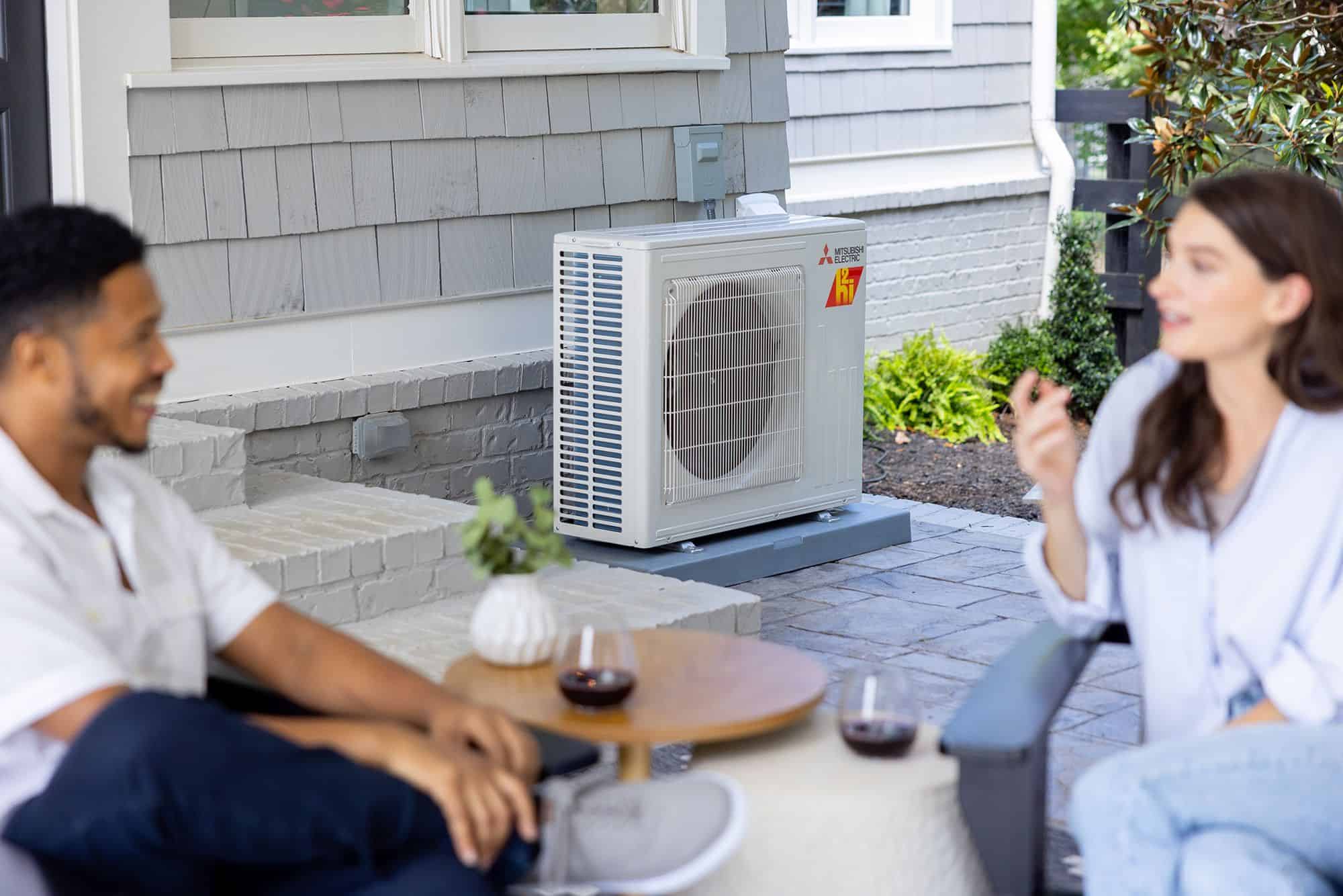 Outdoor AC unit on patio with people relaxing, efficient cooling system installation.